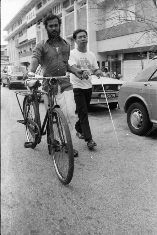CYCLIST HELPING BLIND MAN