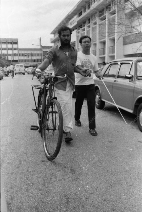 CYCLIST HELPING BLIND MAN